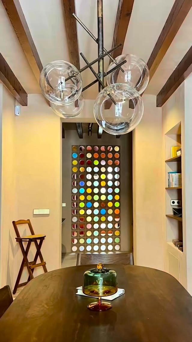 Colorful circular glass pane room divider standing in a doorway between two warm-toned rooms.