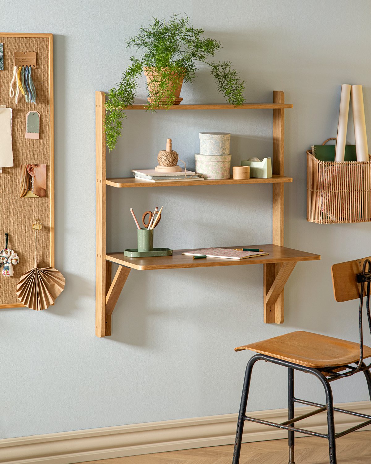 Wooden wall-mounted desk with shelves and a chair against a light blue wall.