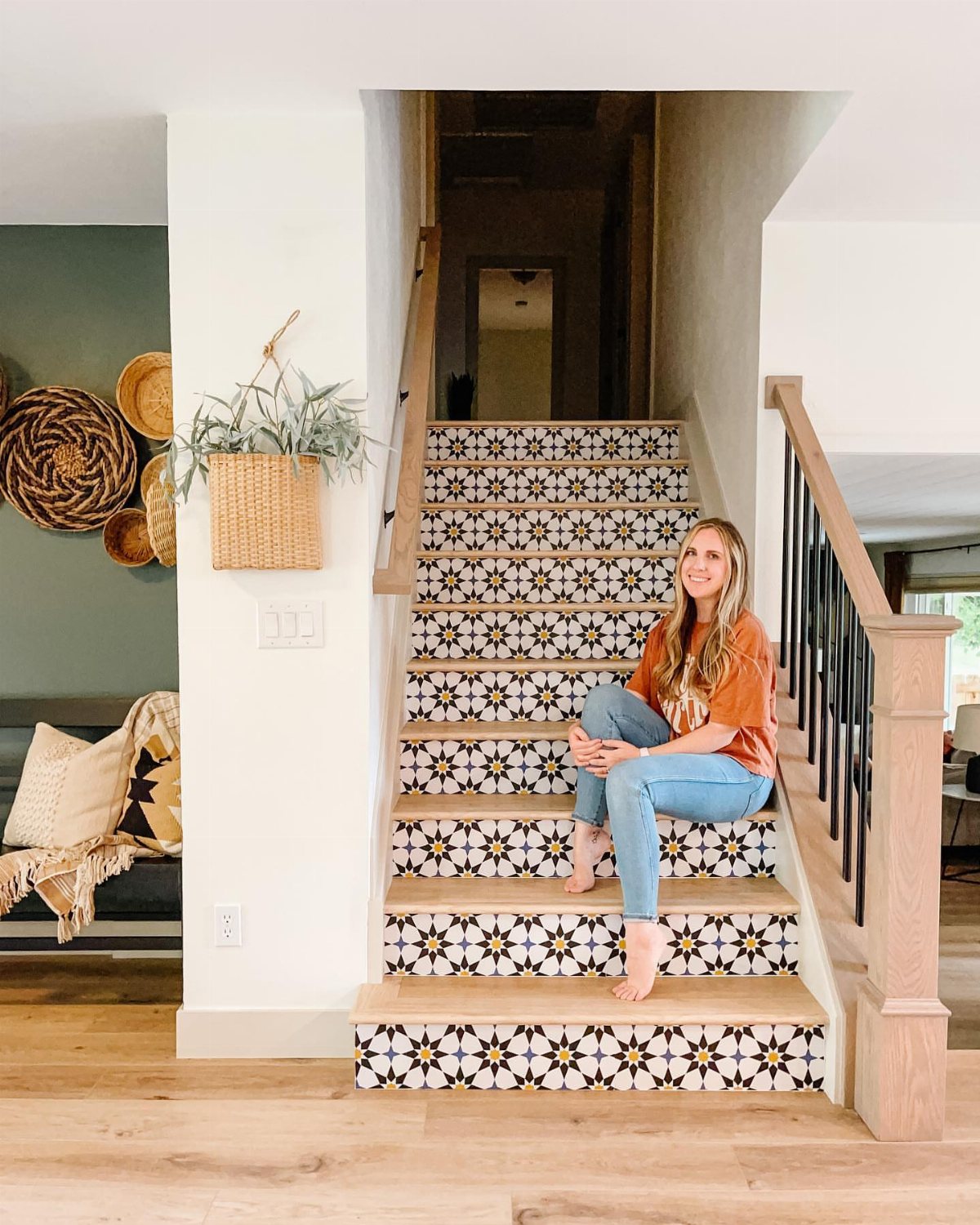 A woman sitting on stairs featuring patterned wallpaper on the vertical risers.