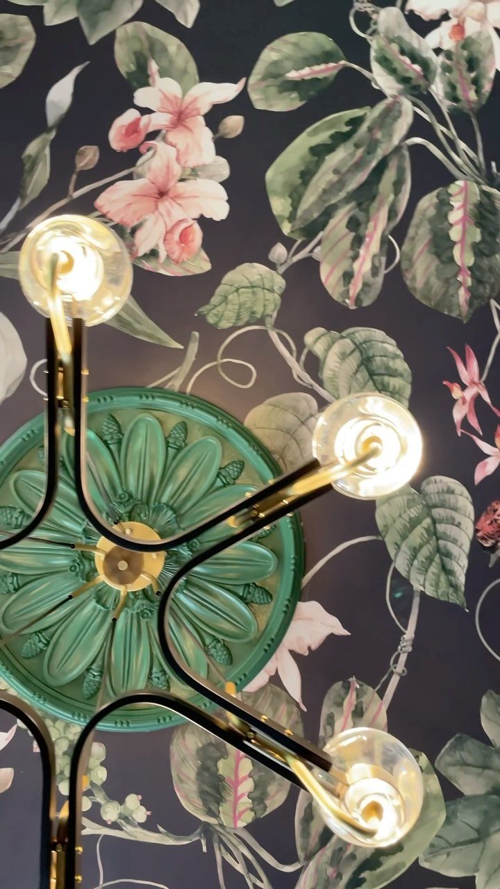 Floral patterned wallpaper on a ceiling with a green medallion and gold light fixture.