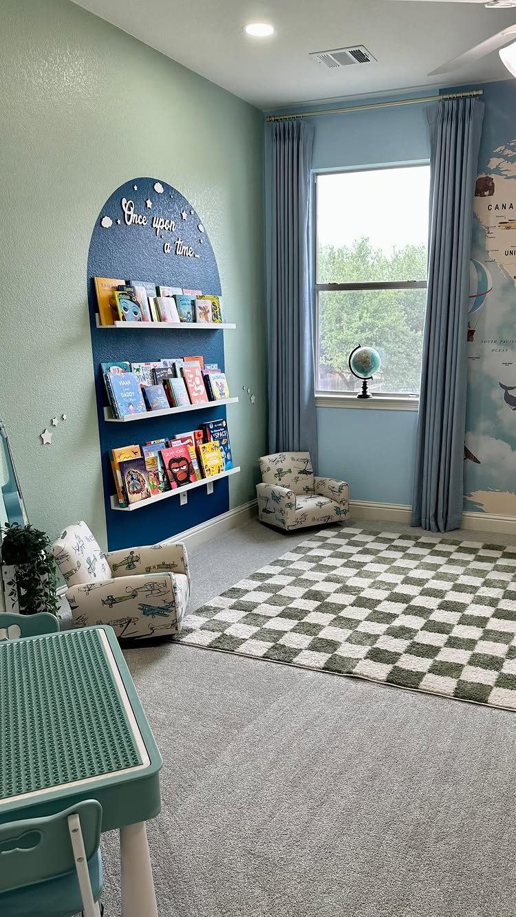 Blue arched bookshelf filled with books, two small armchairs, and a checkered rug in a bright playroom.