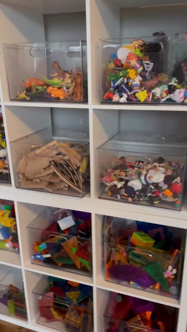 7 Toy Organization Ideas for Playrooms and Living Spaces 2 Clear plastic bins filled with colorful toys organized inside a white cube storage unit.