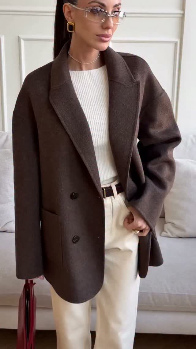 Woman wearing an oversized dark brown wool blazer with cream trousers and a white ribbed top.
