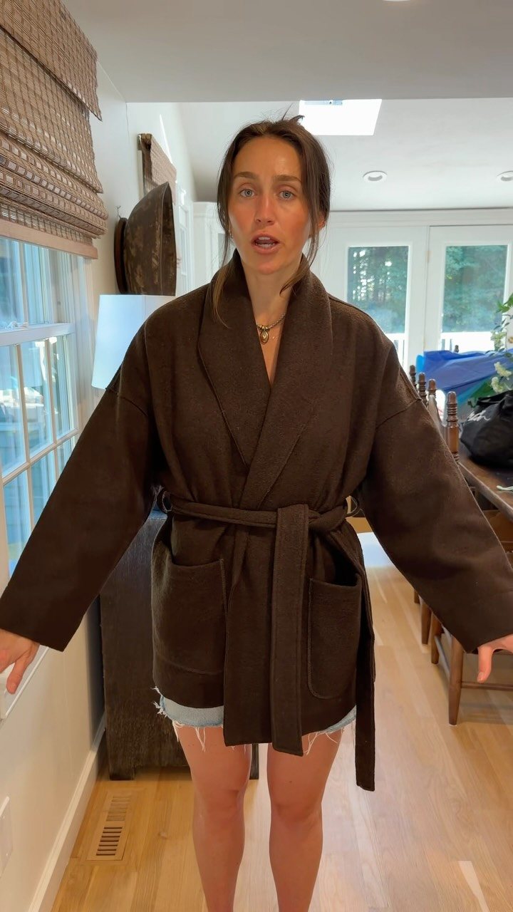 Woman wearing a dark brown oversized wrap coat with a waist tie.