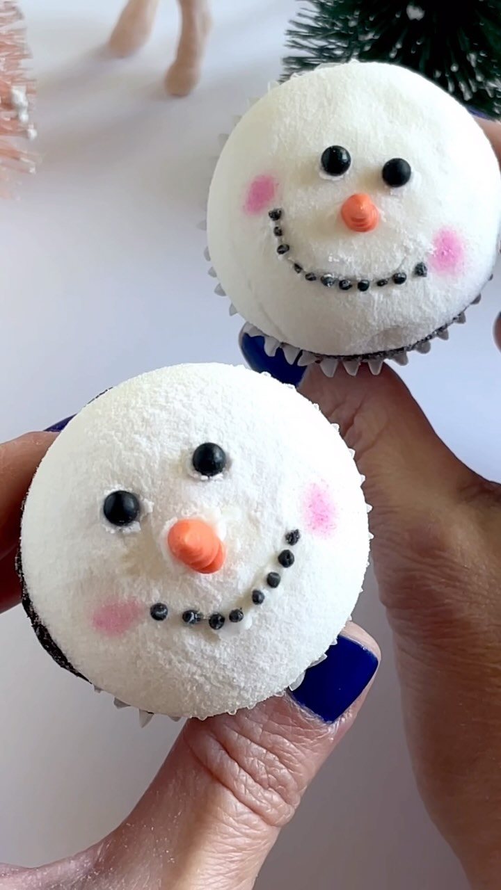 9 Christmas Cupcakes with Santa Hats, Snowmen and Reindeer 1 Two snowmen decorated cupcakes held by hands with blue nail polish.
