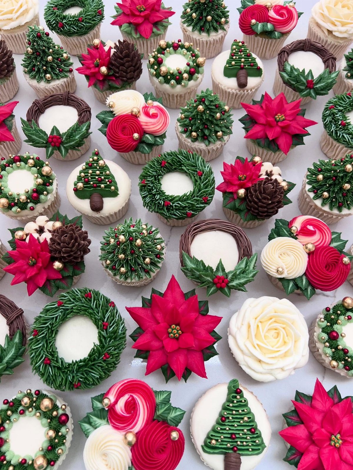 9 Christmas Cupcakes with Santa Hats, Snowmen and Reindeer 4 Assorted Christmas cupcakes featuring green wreaths, red poinsettias, and small green Christmas trees.