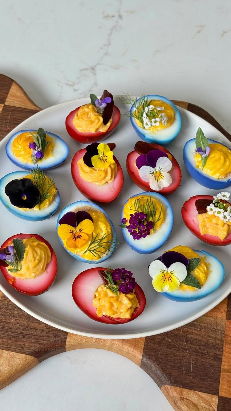 Dyed Deviled Eggs: 5 Ways From Pastel to Bright Pink 5 Deviled eggs with colorful dyed egg whites and edible flowers on a white plate.