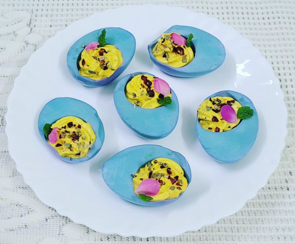 Dyed Deviled Eggs: 5 Ways From Pastel to Bright Pink 1 Blue dyed deviled eggs topped with pink flower petals on a white plate.
