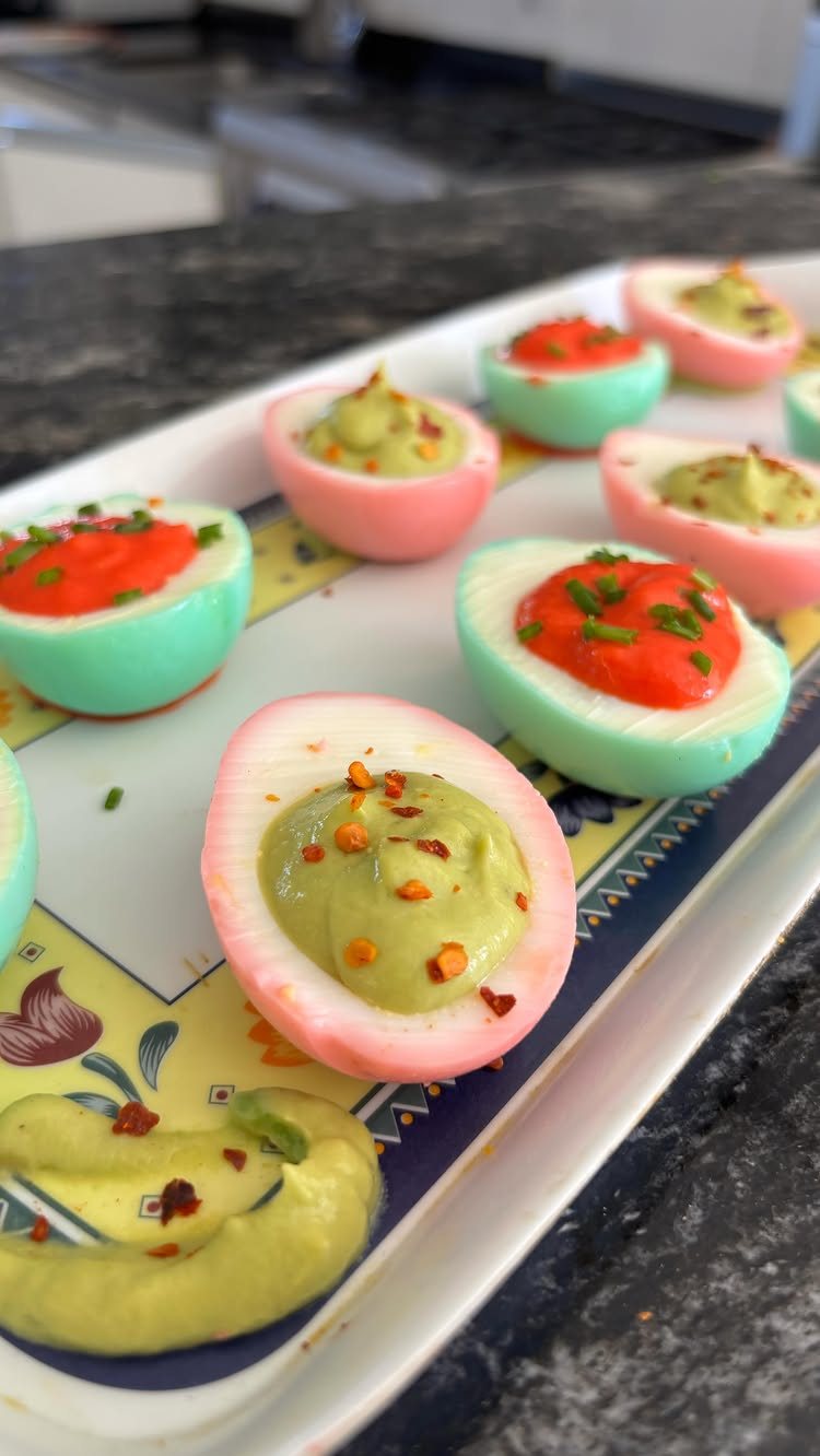 Dyed Deviled Eggs: 5 Ways From Pastel to Bright Pink 2 Pastel pink and blue deviled eggs with green filling on a decorative platter.