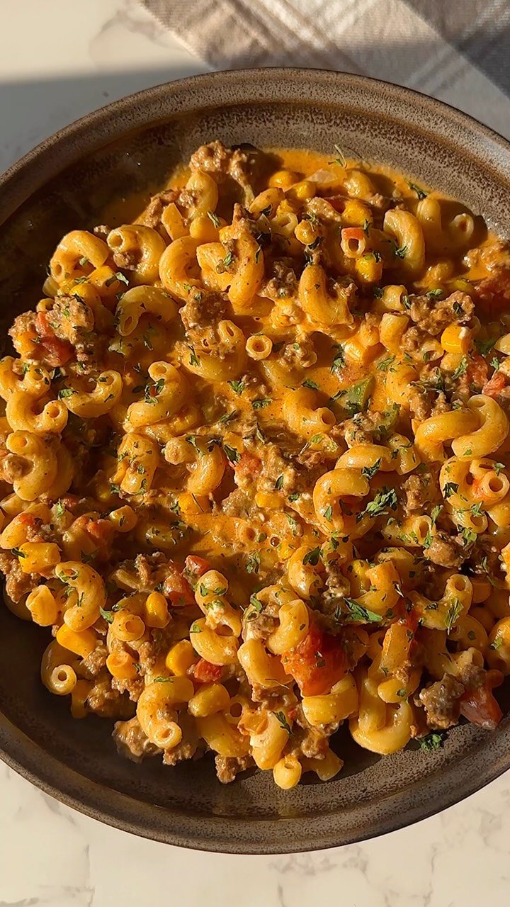 14 Ground Beef Recipes Using Few Ingredients for Low-Stress Weeknights 3 Macaroni pasta mixed with ground beef, melted cheese, and tomatoes in a dark bowl.