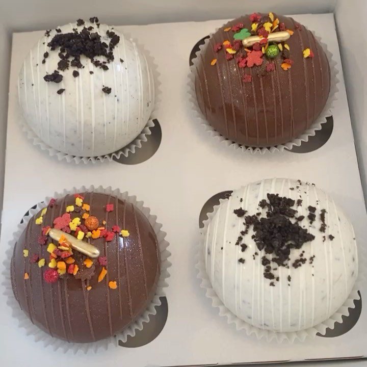 12 Hot Chocolate Bombs for Every Holiday and Skill Level 9 Four decorated hot chocolate bombs in a white box with paper liners.
