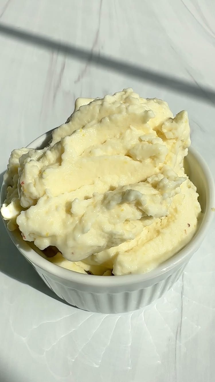 Creamy pale yellow whipped mousse served in a small white ceramic ramekin on a marble surface.