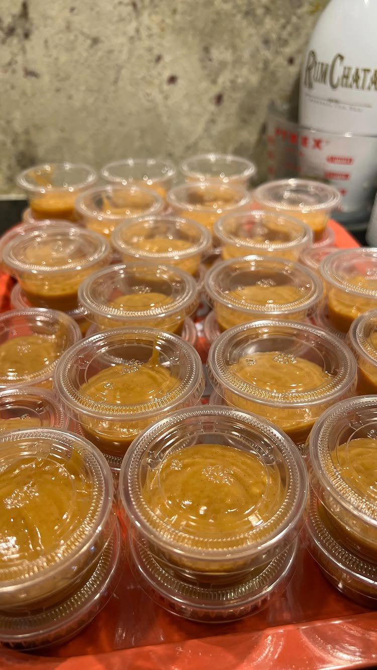 Small clear plastic cups filled with orange pumpkin pudding sitting on a red tray.