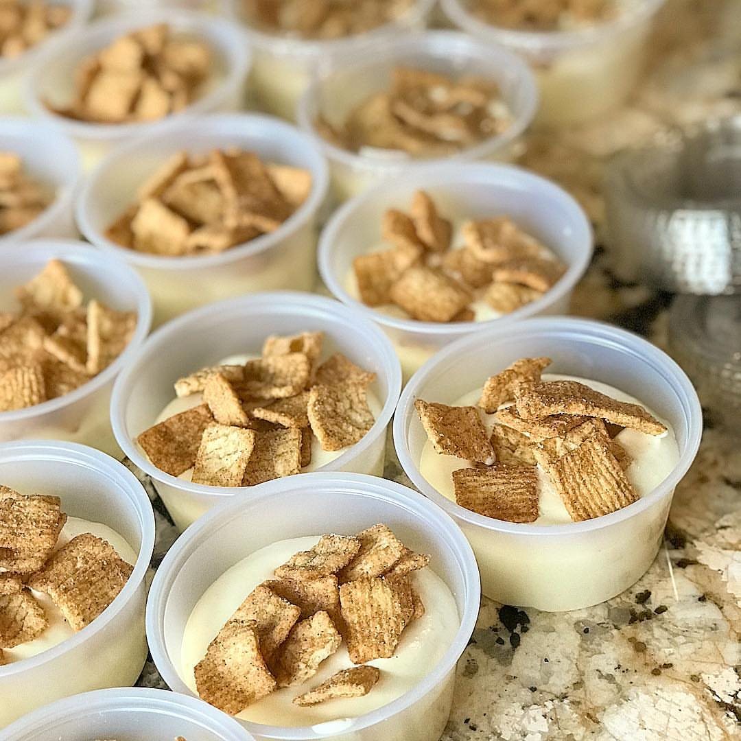 Small plastic shot cups filled with creamy white pudding and topped with crunchy cereal pieces.