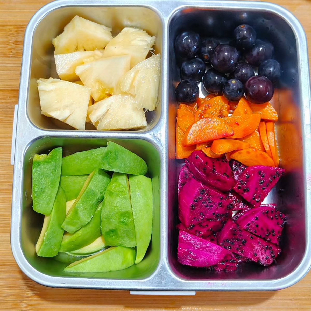 19 School Lunch Ideas for Real Mornings 13 A stainless steel bento box filled with various colorful sliced fruits.