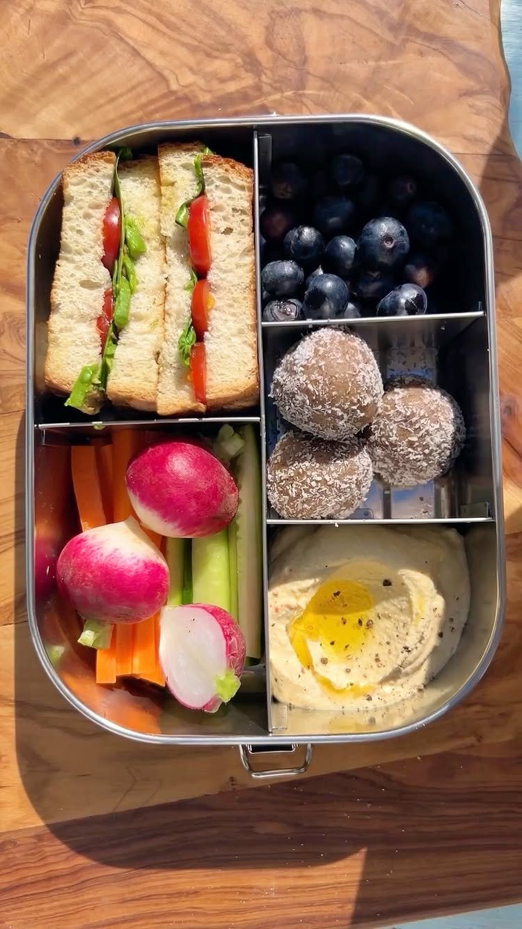 19 School Lunch Ideas for Real Mornings 5 Stainless steel bento box filled with sandwiches, blueberries, energy balls, radishes, carrots, and hummus.