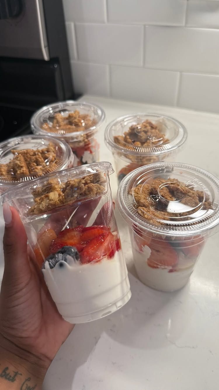 19 School Lunch Ideas for Real Mornings 17 Four clear plastic cups containing layered yogurt, fresh strawberries, blueberries, and crunchy granola topping.