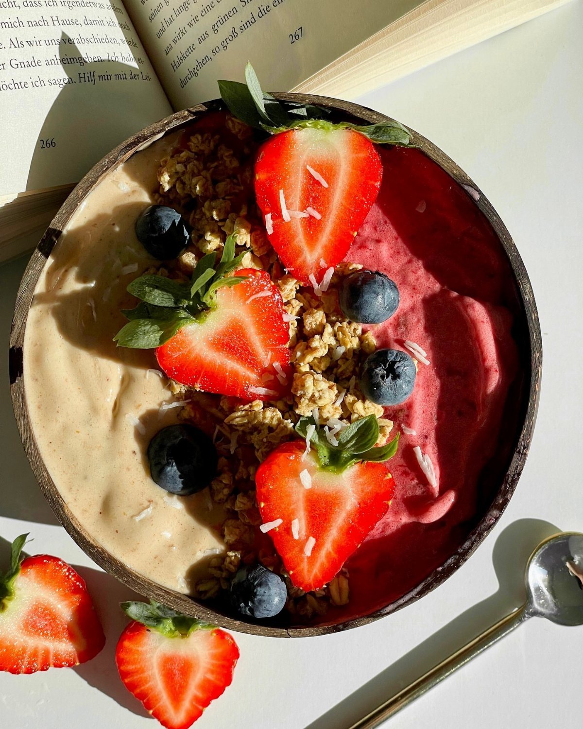 13 Smoothie Bowl Recipes with Photos for Every Morning 11 A smoothie bowl with tan and magenta bases topped with granola, strawberries, and blueberries.