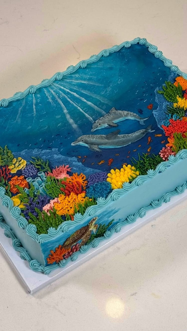 8 Undersea Cake Ideas From Fondant Reefs to Jellyfish Buttercream 8 A rectangular blue cake decorated with dolphins, colorful coral reefs, and a sea turtle.