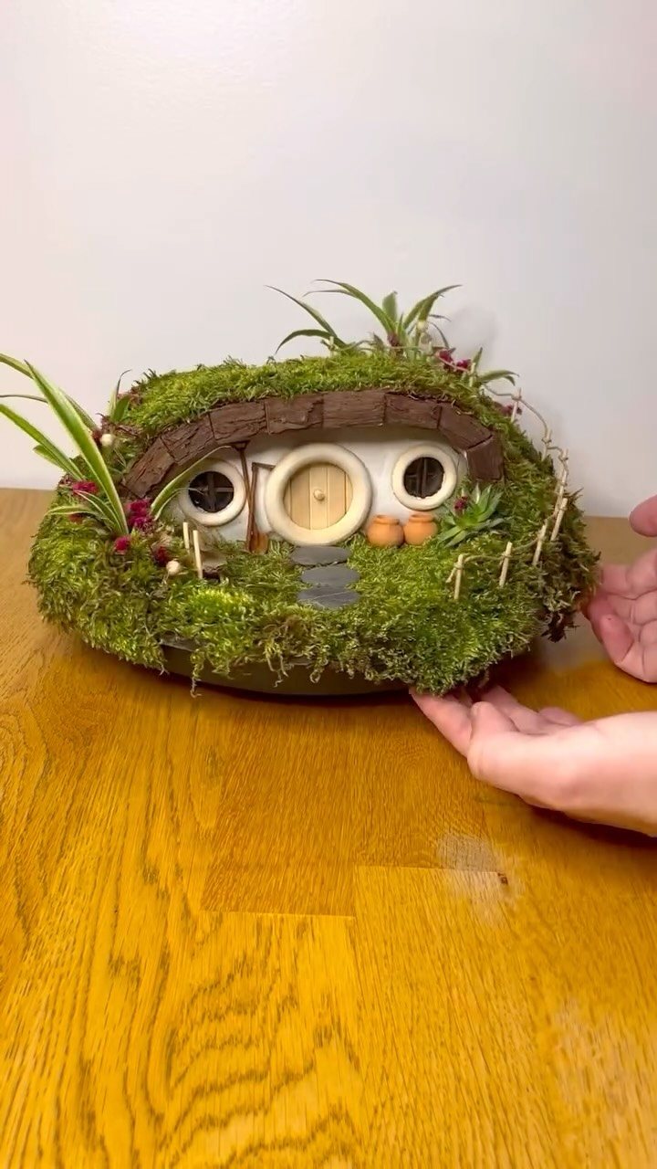 13 Fairy Garden Ideas: Broken Pots to Teacup Worlds 11 A miniature mossy fairy house with tiny windows and a round door held in hands.