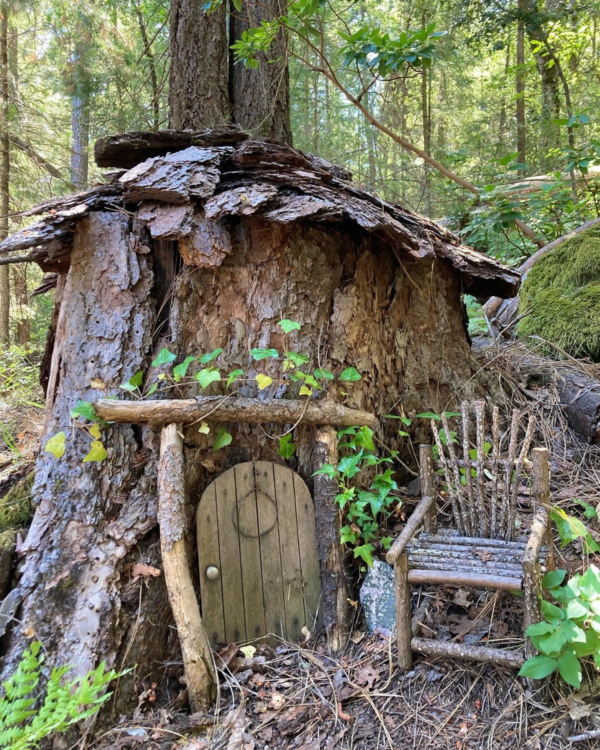 13 Fairy Garden Ideas: Broken Pots to Teacup Worlds 6 A tree stump fairy house with a small wooden door and a miniature twig chair.