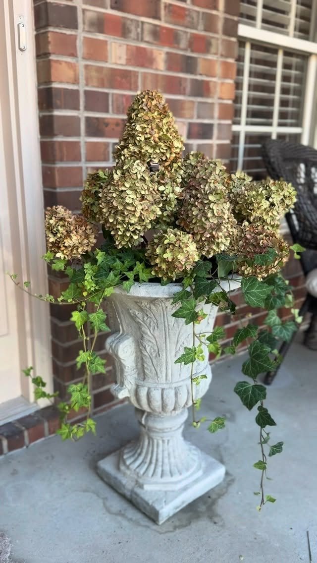 Fall Planter Ideas: 12 Container Combos for Color, Foliage and Texture 12 Dried hydrangea blooms and green ivy trailing from a stone urn planter on a porch.