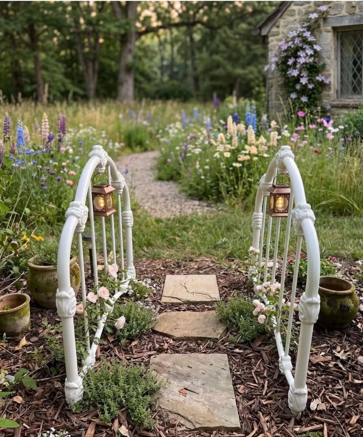 19 Flower Bed Ideas for Every Corner of the Yard 13 A winding gravel path through a wildflower garden framed by white decorative arches and stone steps.