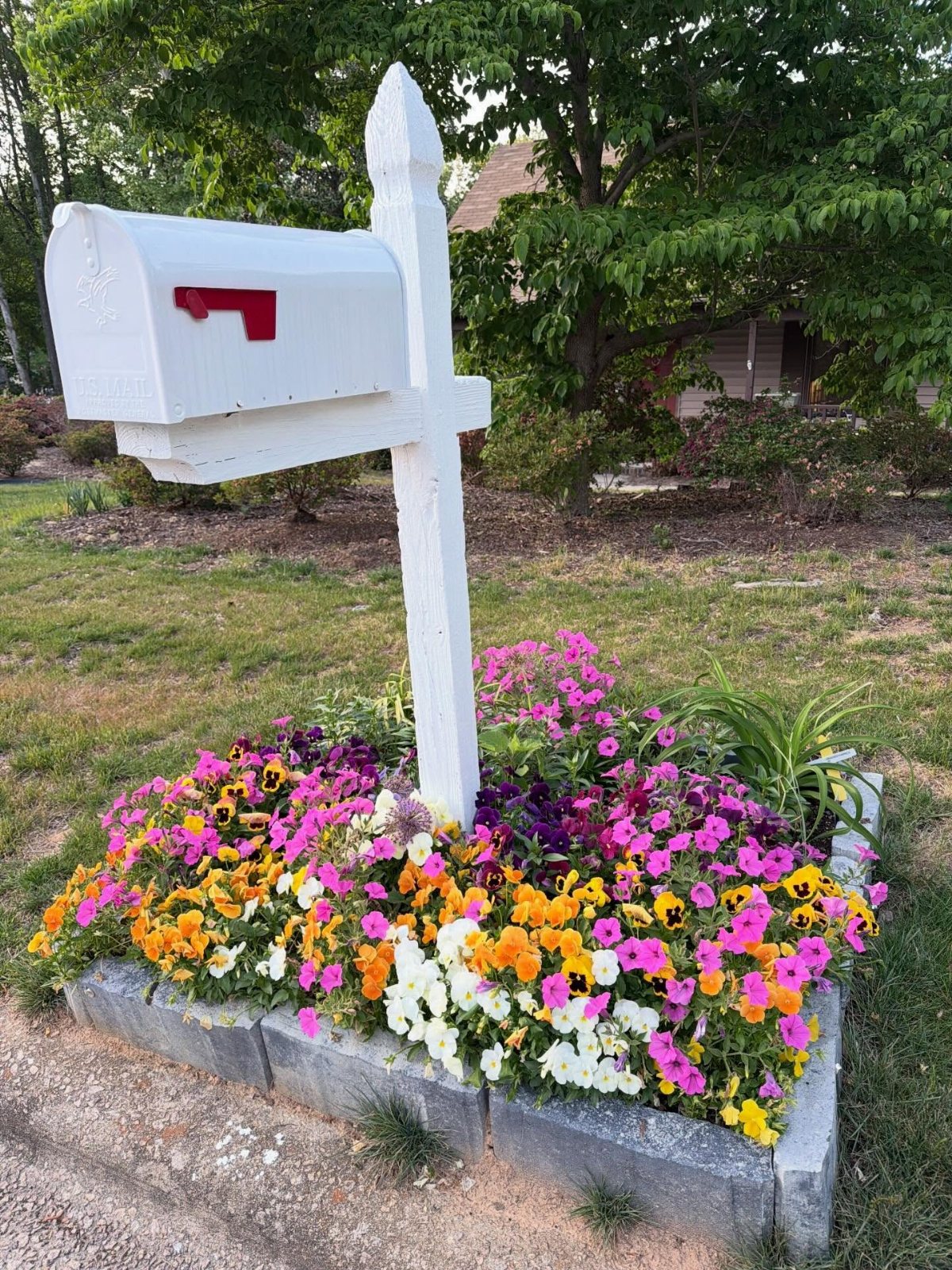 19 Flower Bed Ideas for Every Corner of the Yard 14 White wooden mailbox surrounded by a colorful petunia flower bed with stone edging.