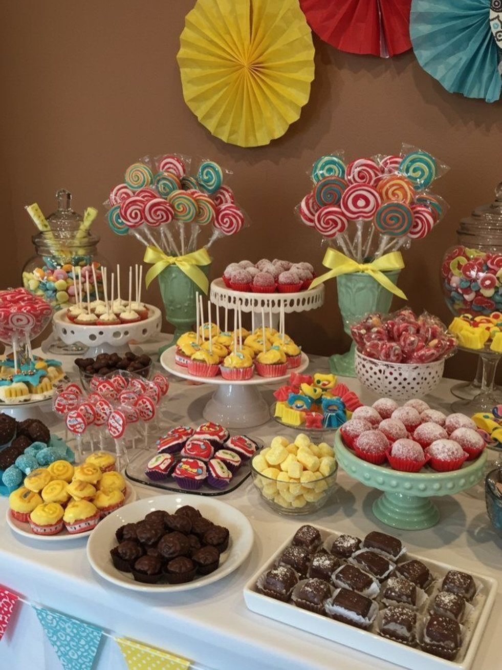 A diverse assortment of colorful candies, lollipops, and cupcakes arranged on a dessert table.