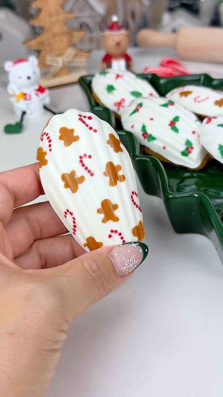 Candy Cane Themed Party: 9 Ideas for Decor and Desserts 9 A hand holding a white iced cookie decorated with red candy cane and gingerbread man patterns.