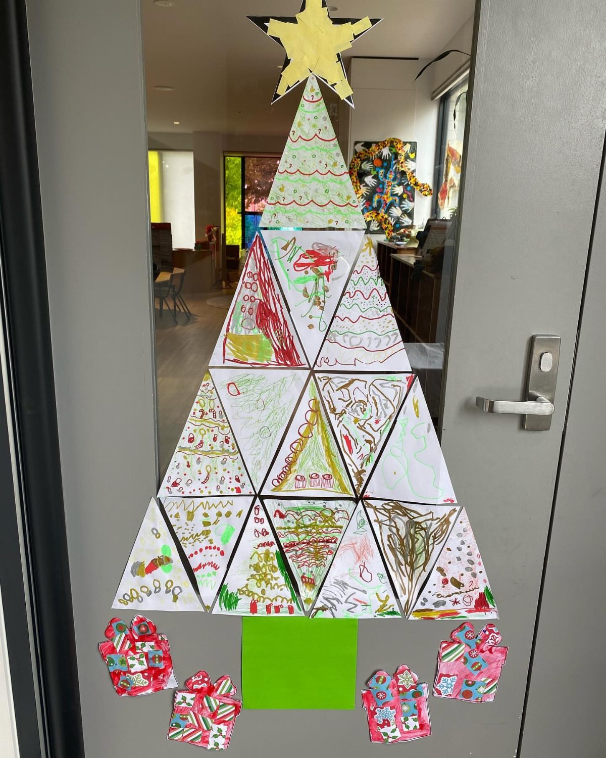 A Christmas tree made of student drawings on a classroom door with a yellow star.