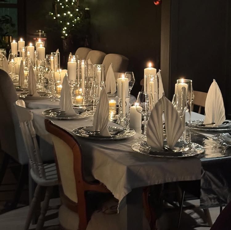 Christmas Table Place Setting Ideas: 16 Styles to Try 11 A long dining table set with many lit white candles and elegant white napkins.