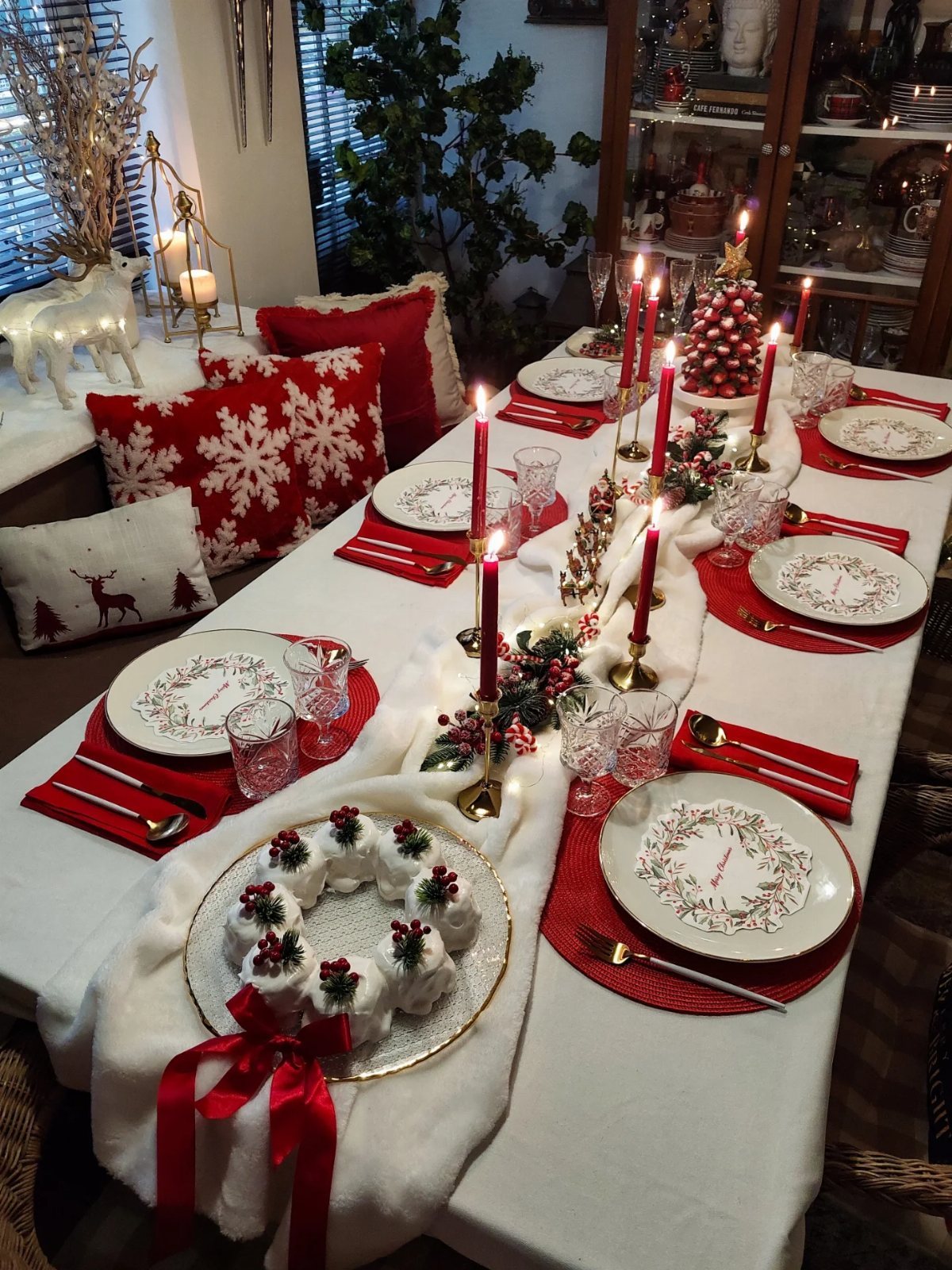 Christmas Table Place Setting Ideas: 16 Styles to Try 9 A festive Christmas table setting with red placemats, white patterned plates, and red taper candles.