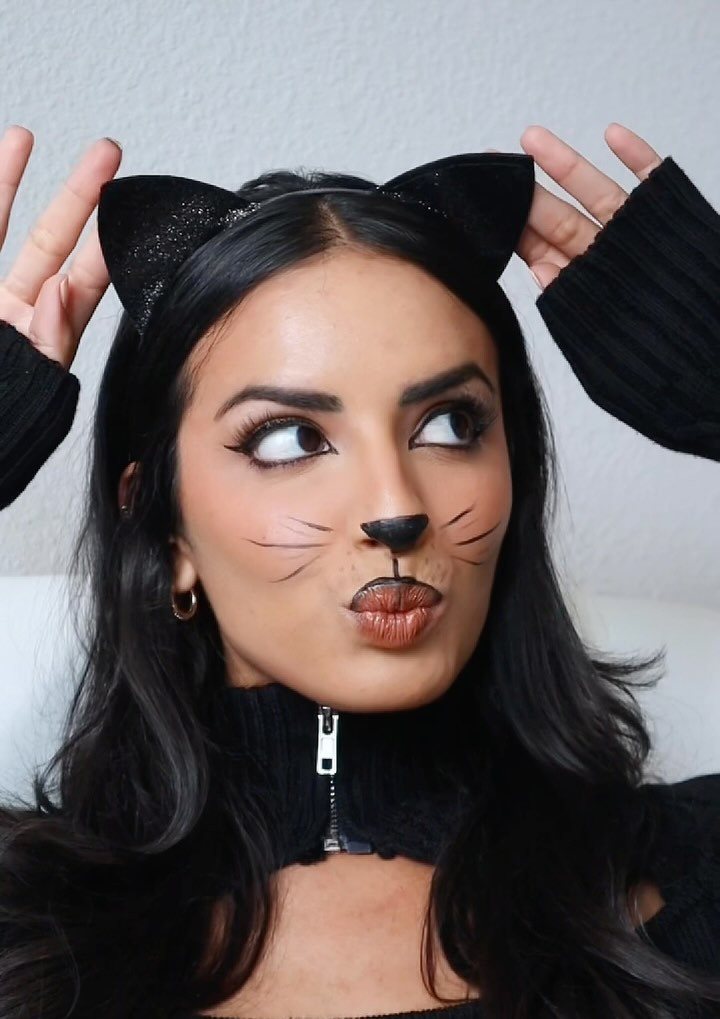 Woman with dark hair wearing cat ears and minimalist cat face makeup.