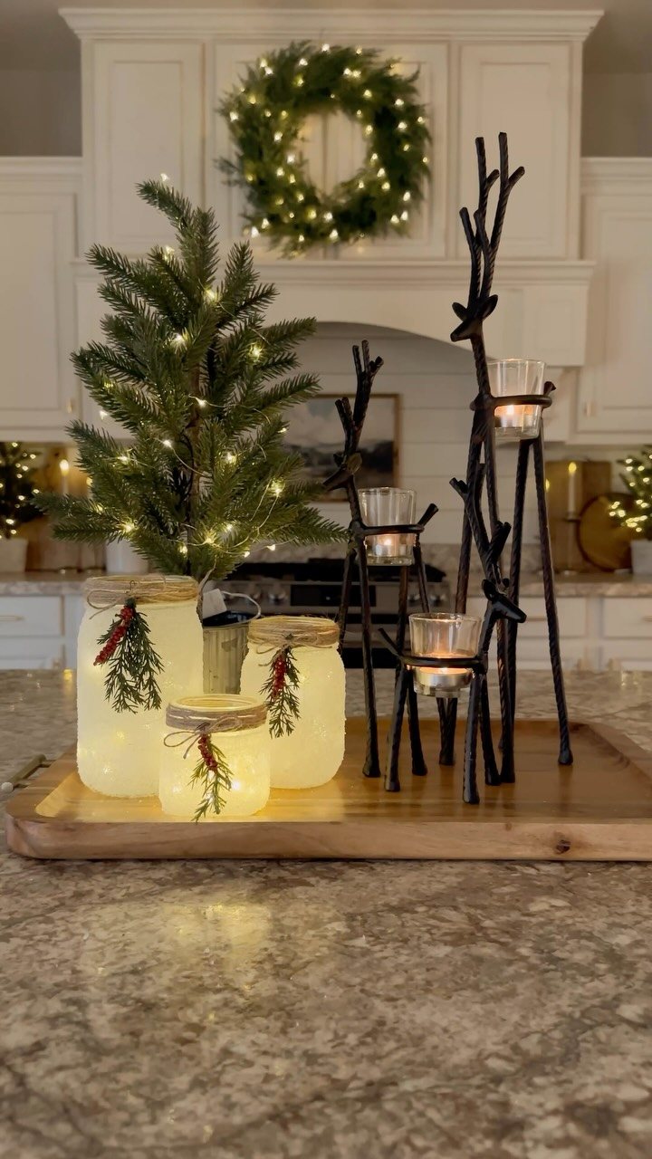 14 Decorating Cheap for Christmas Ideas for 2026 6 Frosted mason jars with lit candles and evergreen sprigs arranged on a wooden tray.