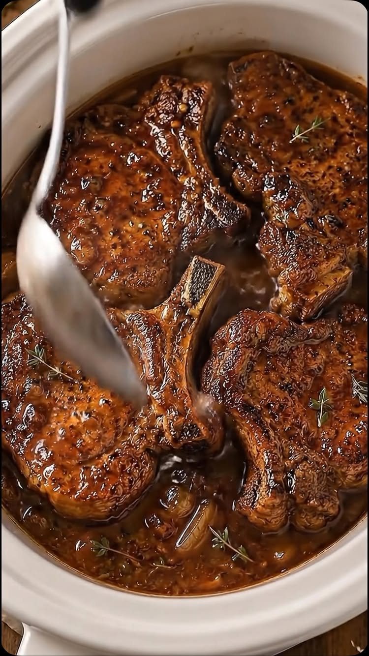 28 Easy Christmas Eve Dinner Ideas: From Slow Cooker Ham to Wreath Pizza 23 Cooked pork chops in a savory sauce with thyme sprigs inside a white slow cooker.