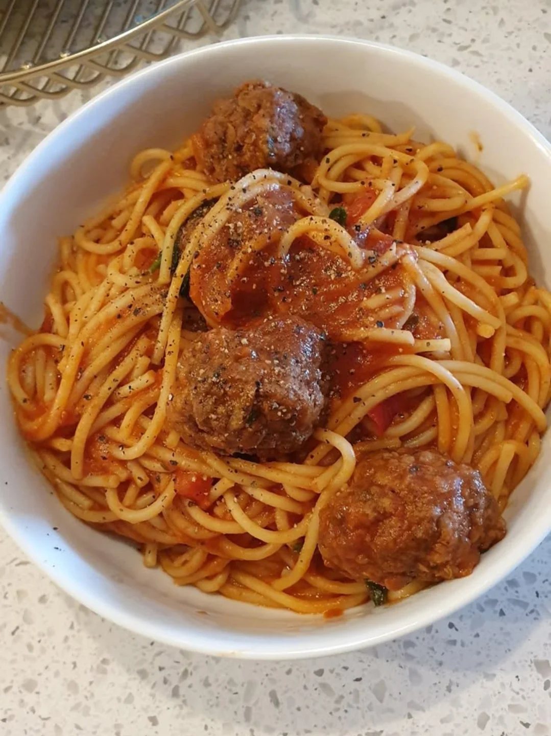 28 Easy Christmas Eve Dinner Ideas: From Slow Cooker Ham to Wreath Pizza 5 Spaghetti with tomato sauce and large meatballs served in a white bowl.