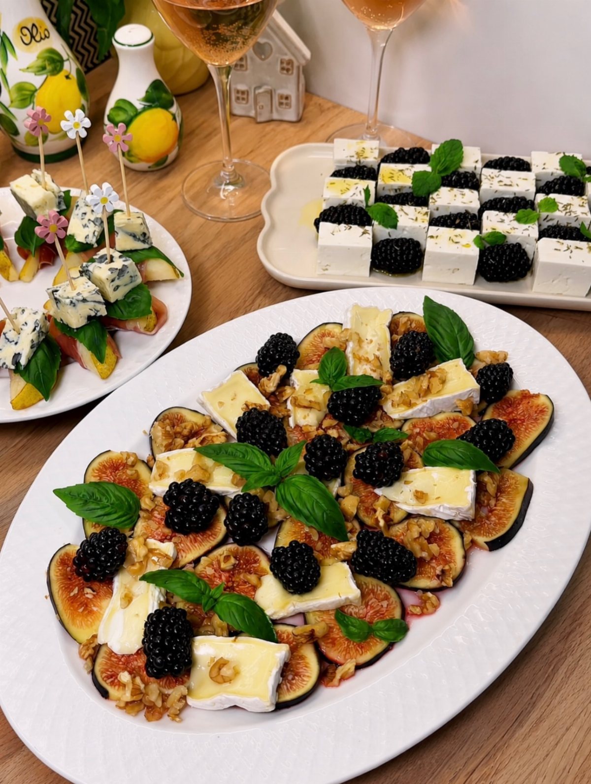 Sliced figs topped with brie cheese, blackberries, and basil leaves on a large white platter.