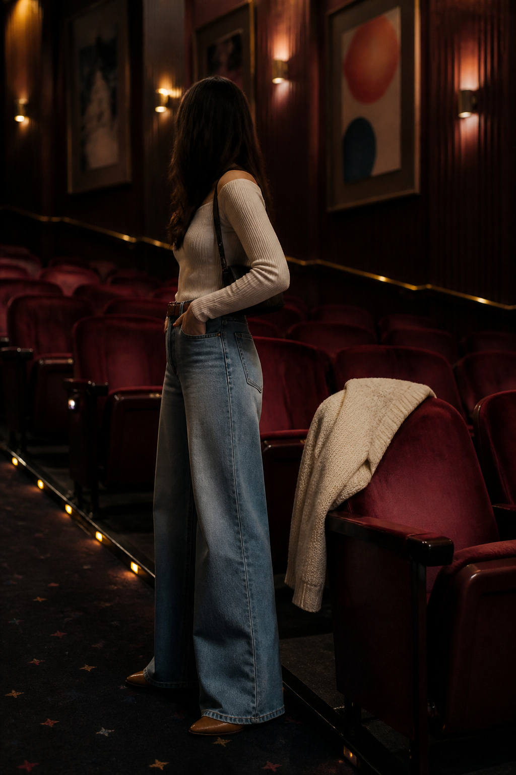 Model wearing relaxed jeans and a fitted top inside a classic cinema.