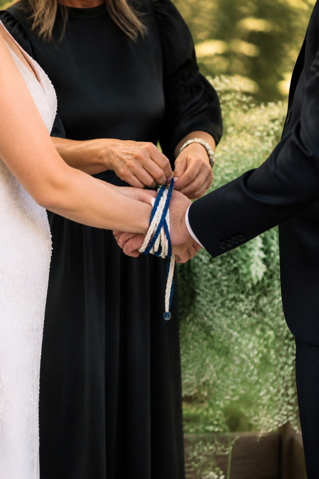 Officiant wrapping a cord around the couple's hands in a figure-eight pattern.