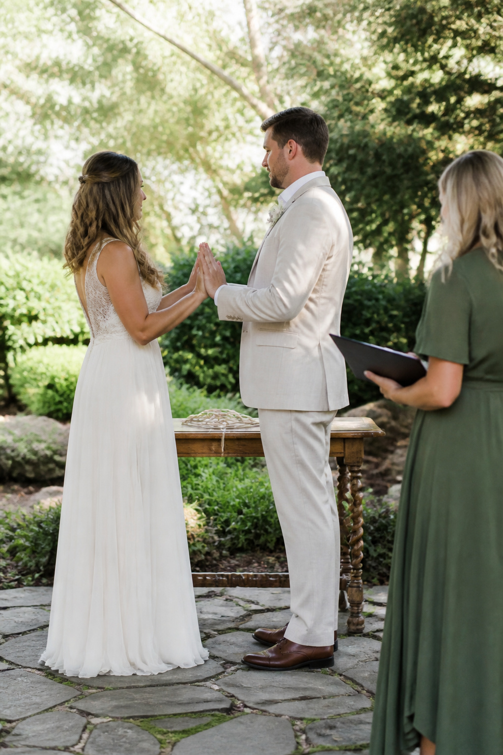 Couple facing each other with hands interlaced in a tranquil garden.