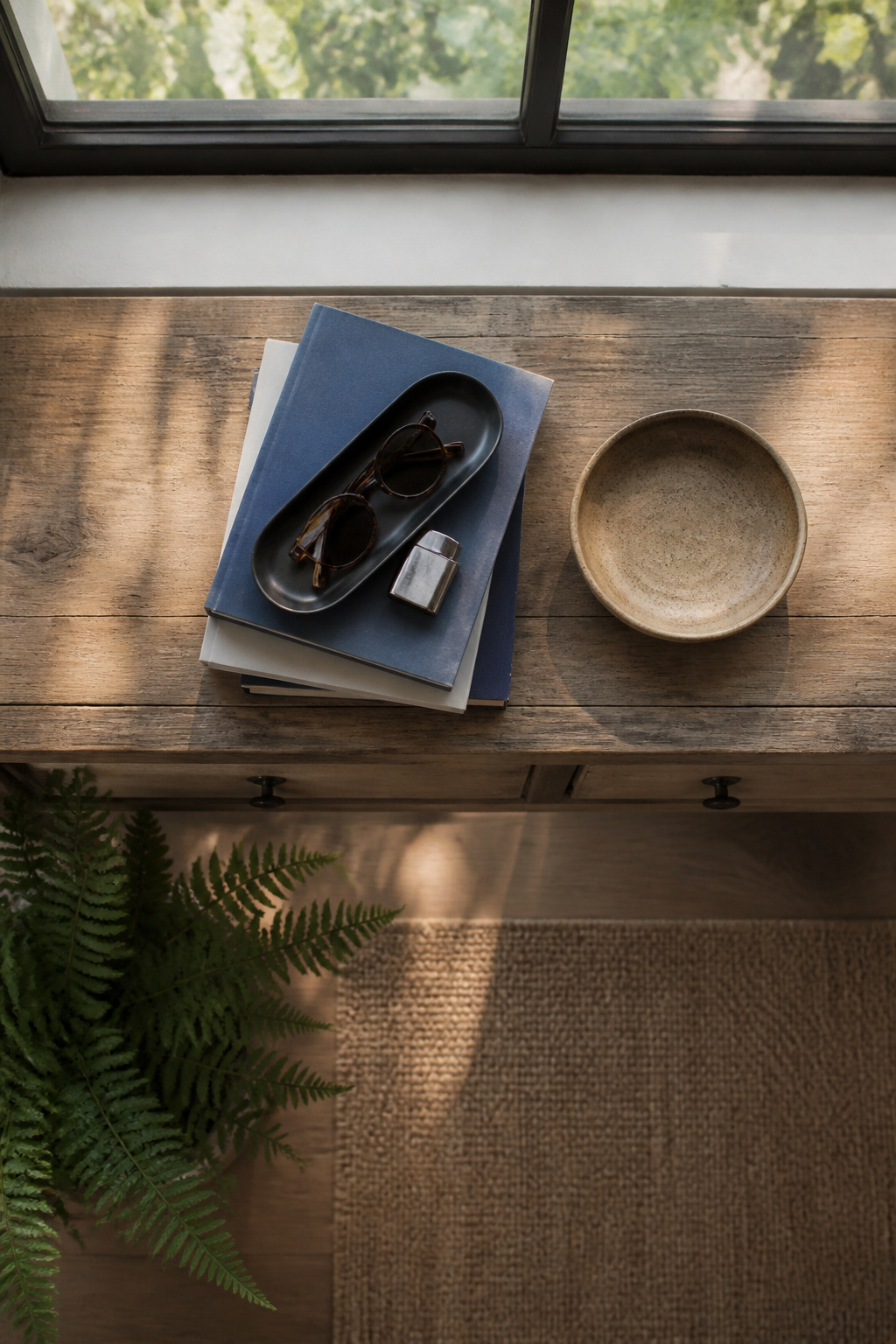 A stack of books and a tray on a console table.