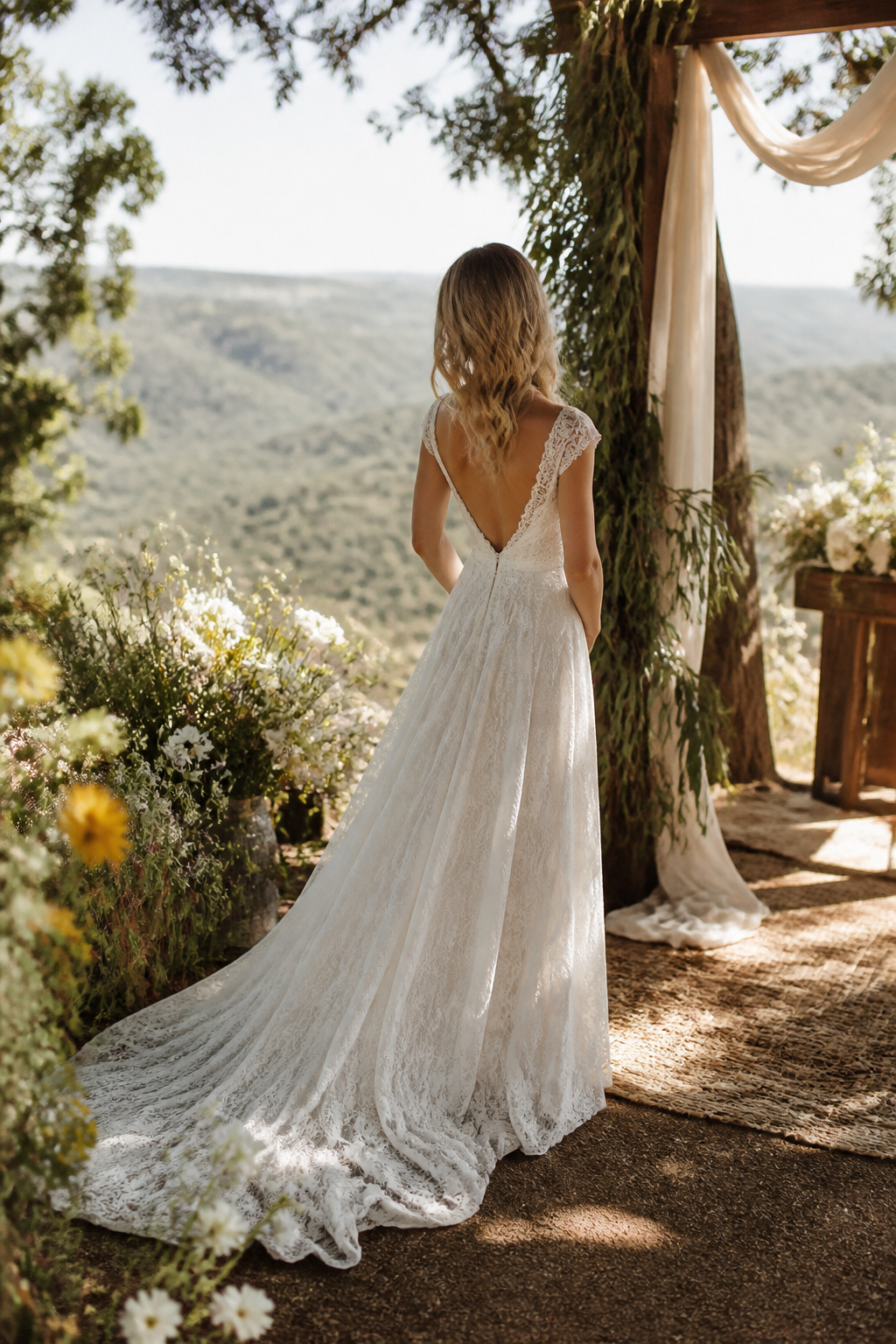 A bride in a flowy A-line dress stands on a hillside.