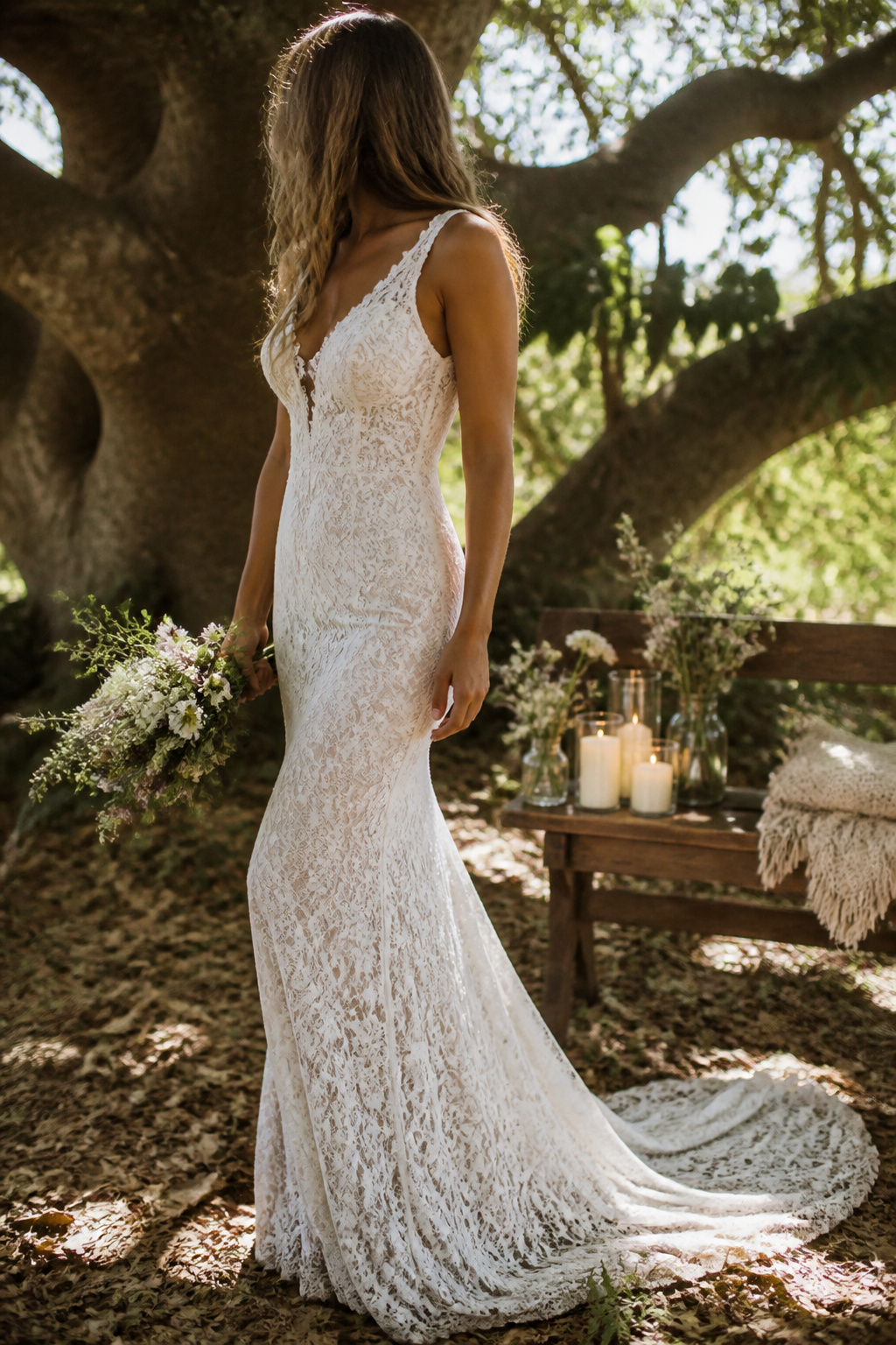 A bride wearing a fitted lace wedding dress under a fig tree.