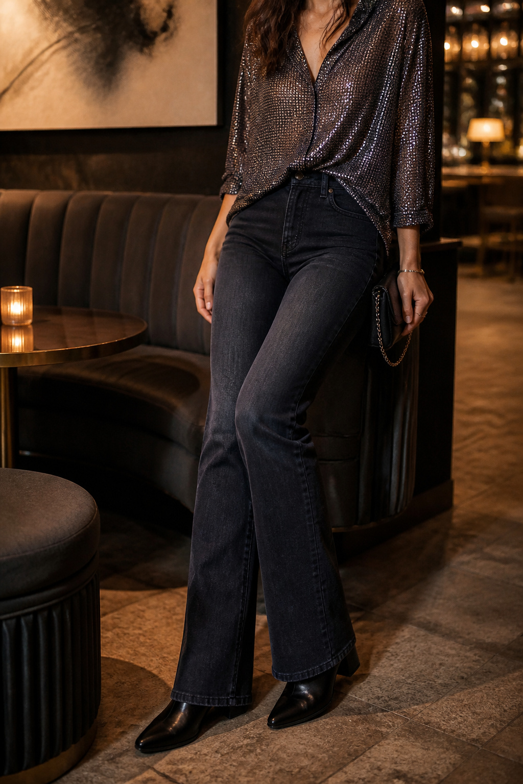 A model wears dark wash jeans and a sequined silk blouse in a lounge.