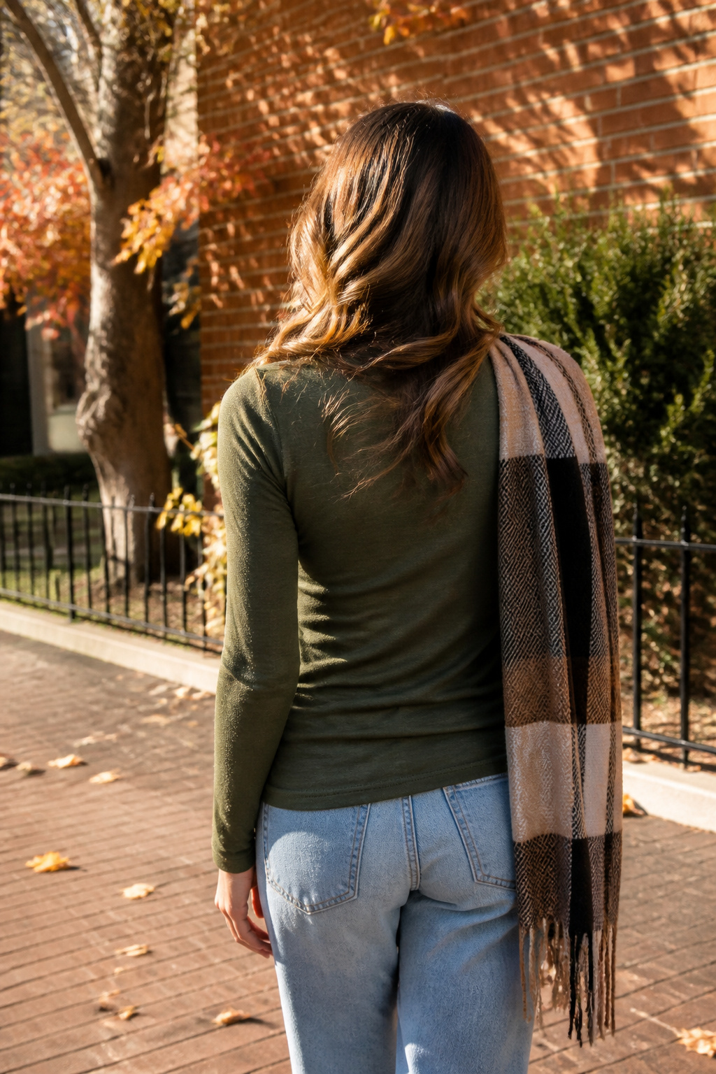 Model in an olive green long-sleeve tee stands on a city street.