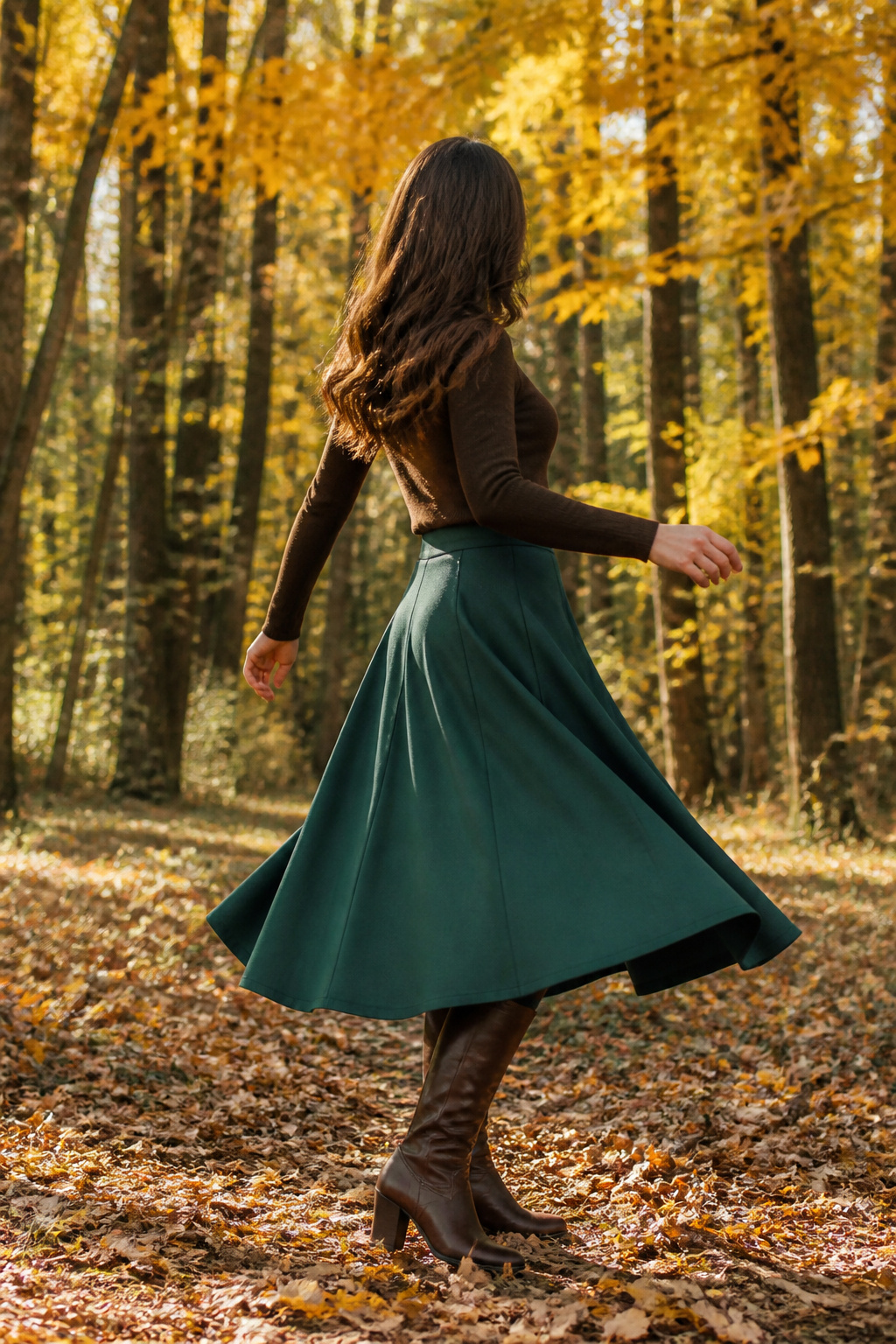 Model in a green wool skirt surrounded by autumn leaves.