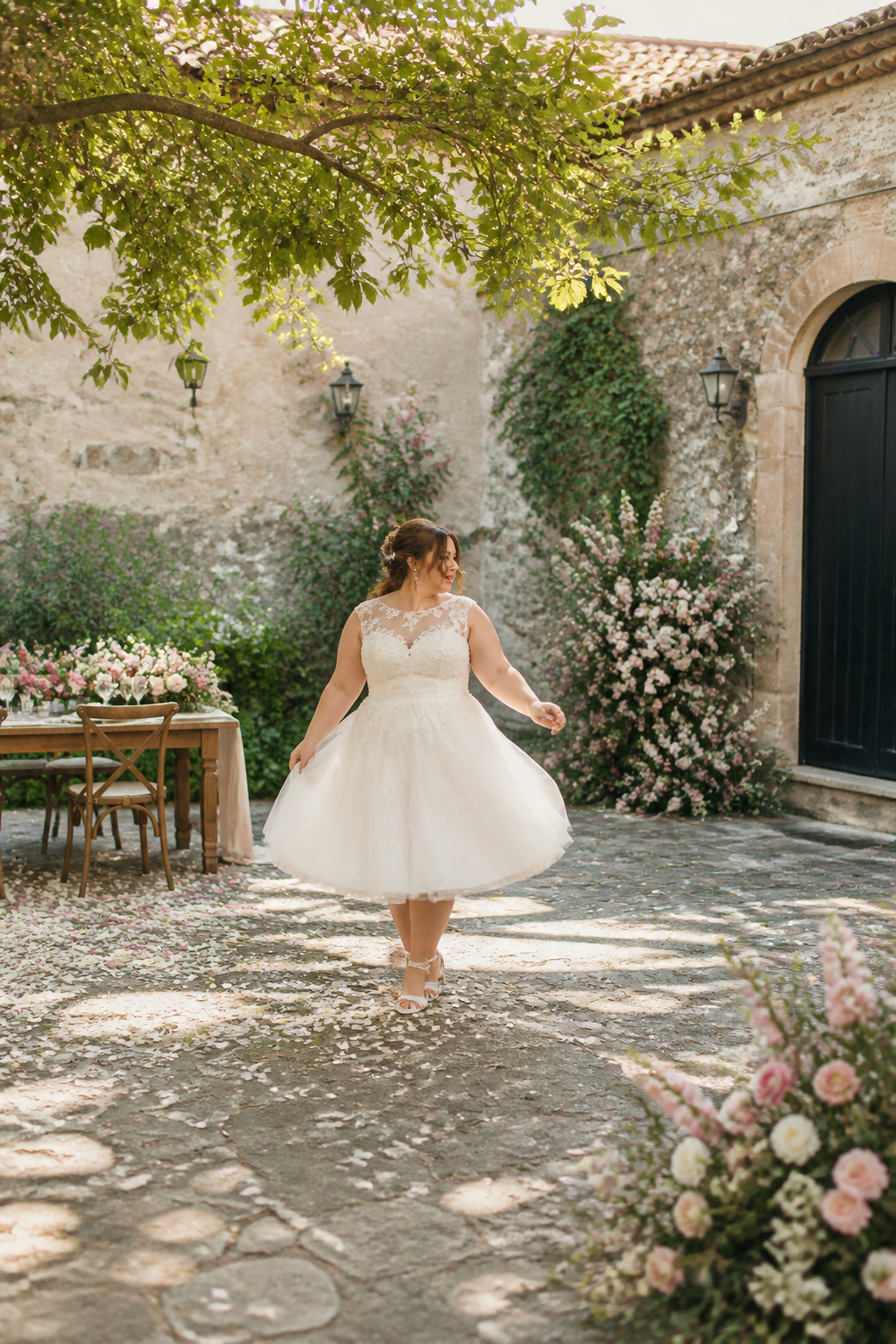 A plus-size tea-length wedding dress with a defined waist and flared skirt.