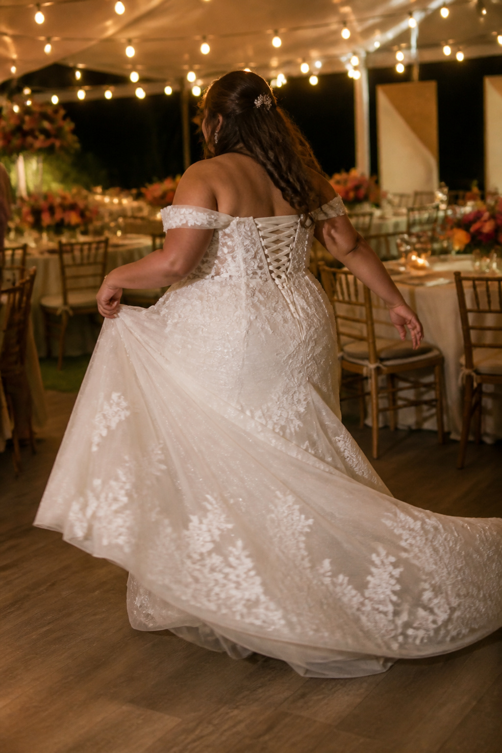 A plus-size bride dancing in a wedding dress at a reception.