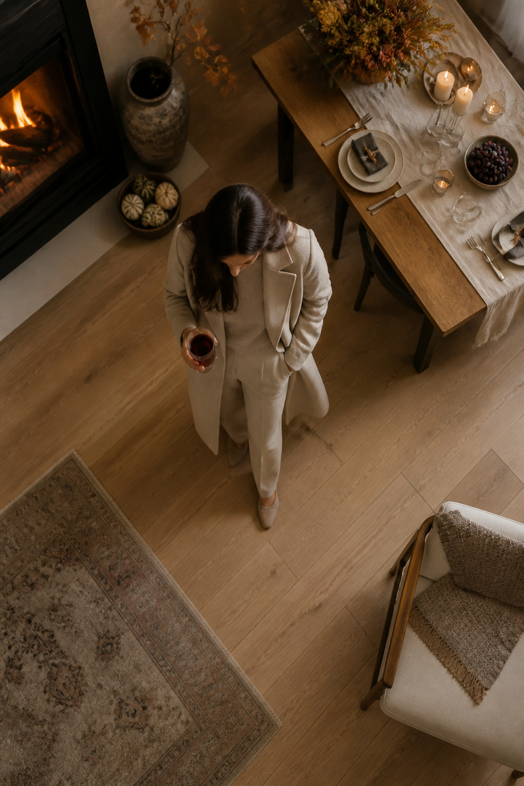 A model wearing a sweater, trousers, and a coat in a cozy setting.